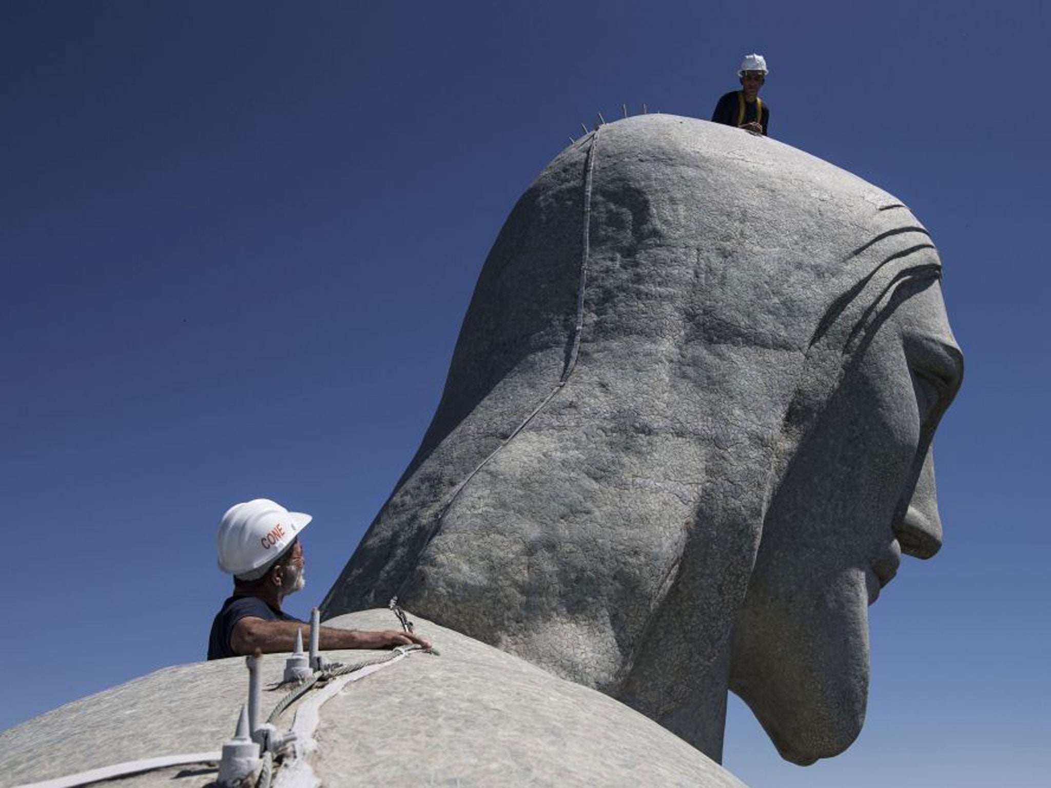 Repair workers examine the top of the Christ Redeemer statue in Rio de Janeiro
