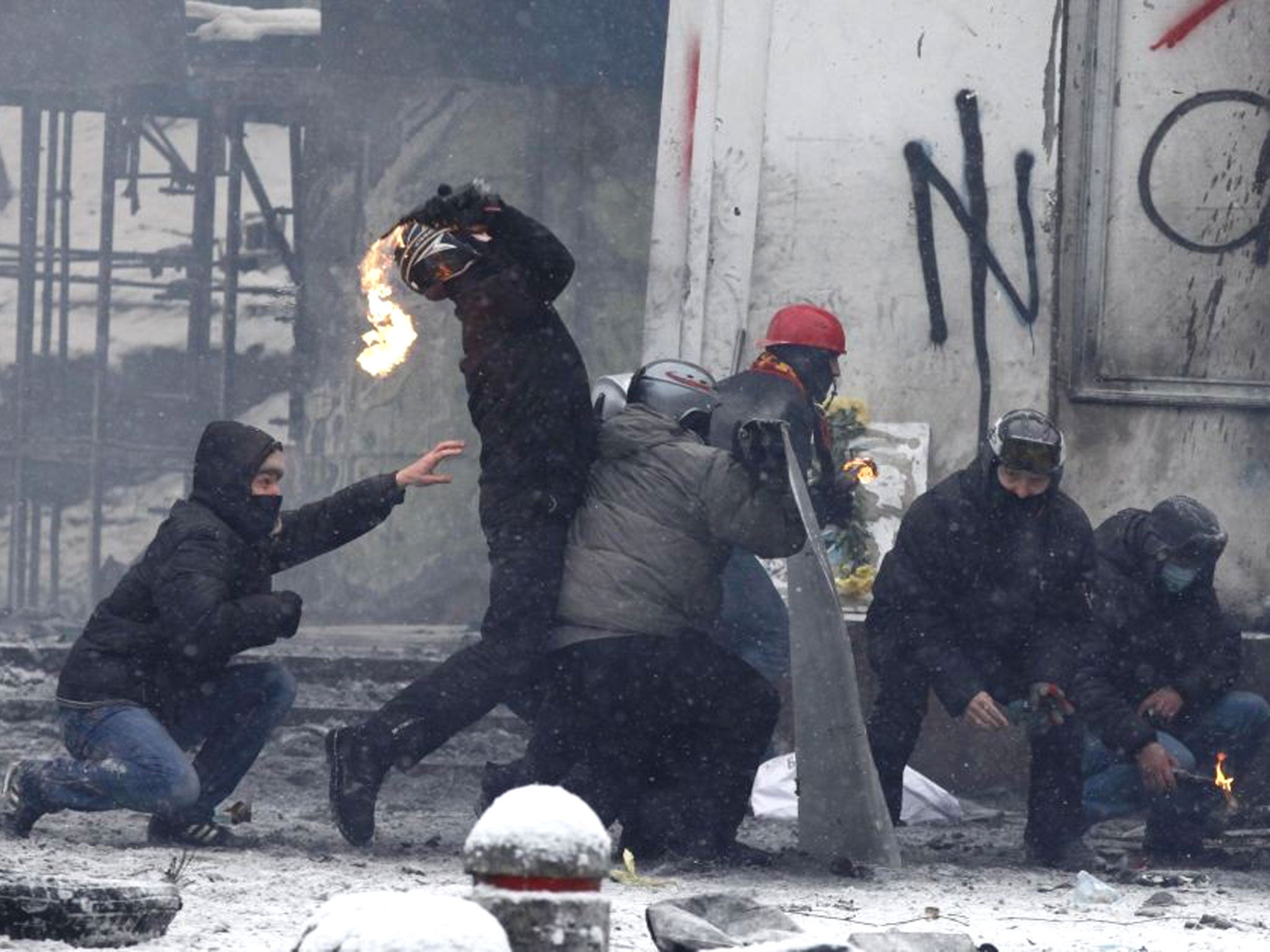 A pro-European protester throws a Molotov cocktail towards riot police during clashes in Kiev