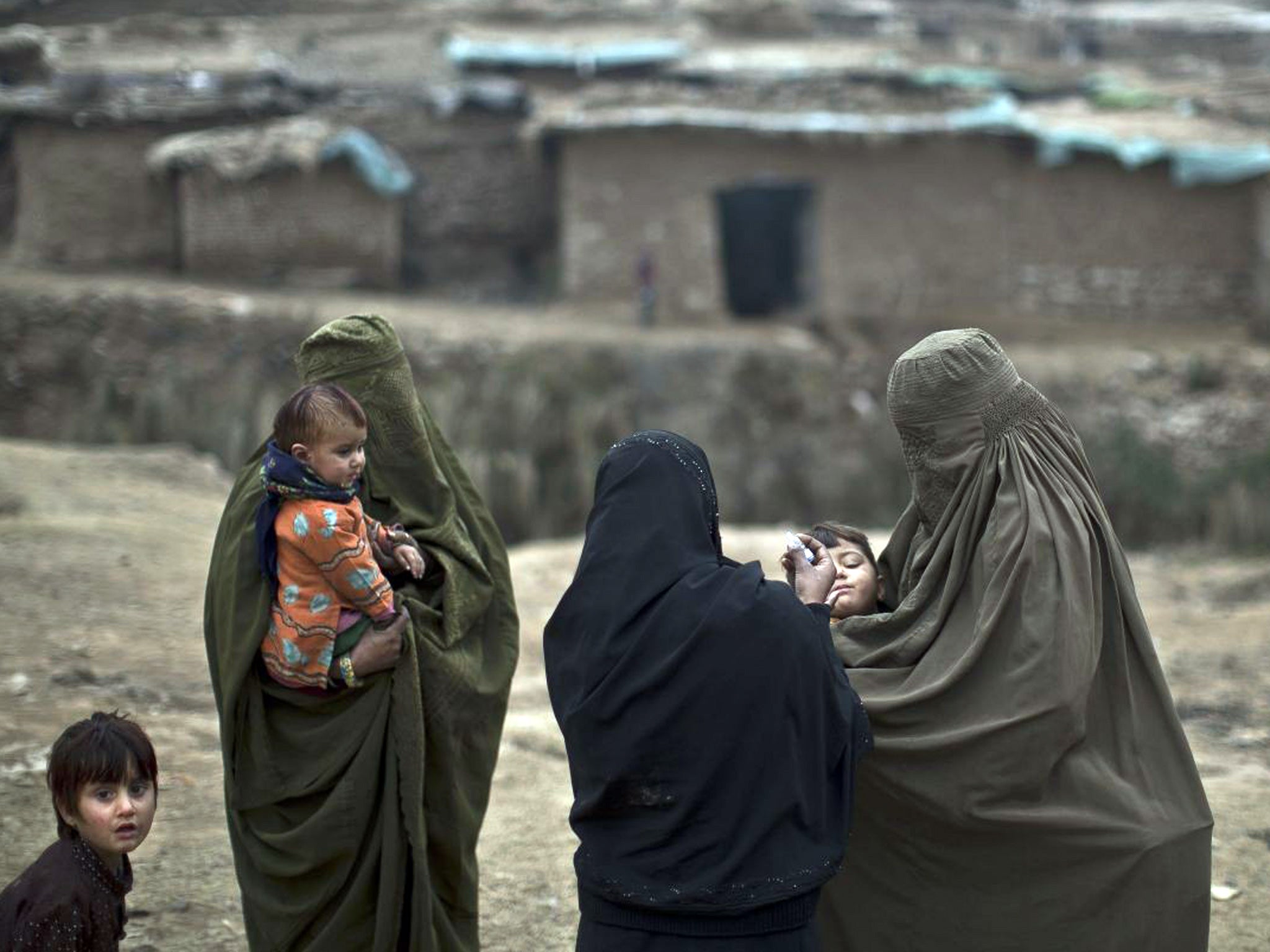 A Pakistani health worker gives a polio vaccine to children in a poor neighborhood that hosts displaced people from Pakistani tribal areas and Afghan refugees, on the outskirts of Islamabad, Pakistan