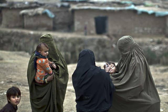 A Pakistani health worker gives a polio vaccine to children in a poor neighborhood that hosts displaced people from Pakistani tribal areas and Afghan refugees, on the outskirts of Islamabad, Pakistan