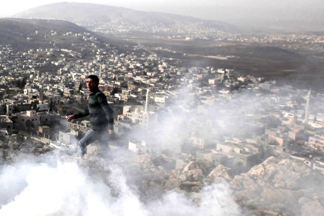 A Palestinian man stands amid tear gas smoke during clashes between Palestinians and Israeli security forces in the village of Beit Furik, near the West Bank city of Nablus