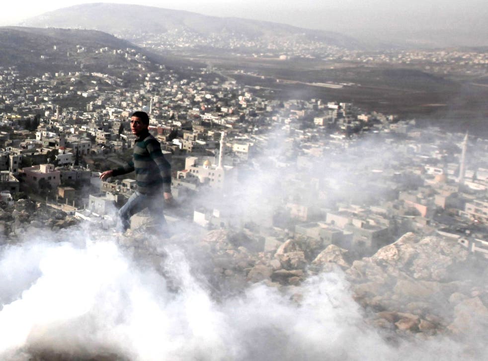A Palestinian man stands amid tear gas smoke during clashes between Palestinians and Israeli security forces in the village of Beit Furik, near the West Bank city of Nablus
