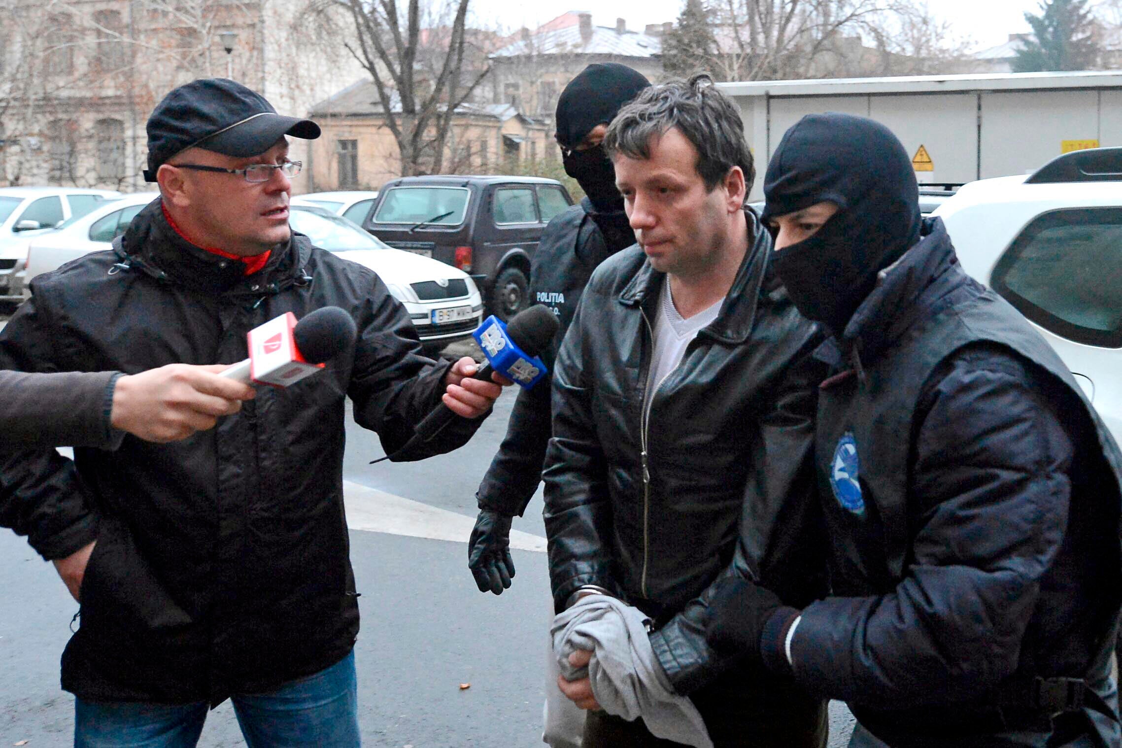 Marcel Lazar Lehel, 40, is escorted by masked policemen in Bucharest, after being arrested in Arad, 550 km (337 miles) west of Bucharest January 22, 2014. Lehel is allegedly the hacker using the nicknames "Guccifer".