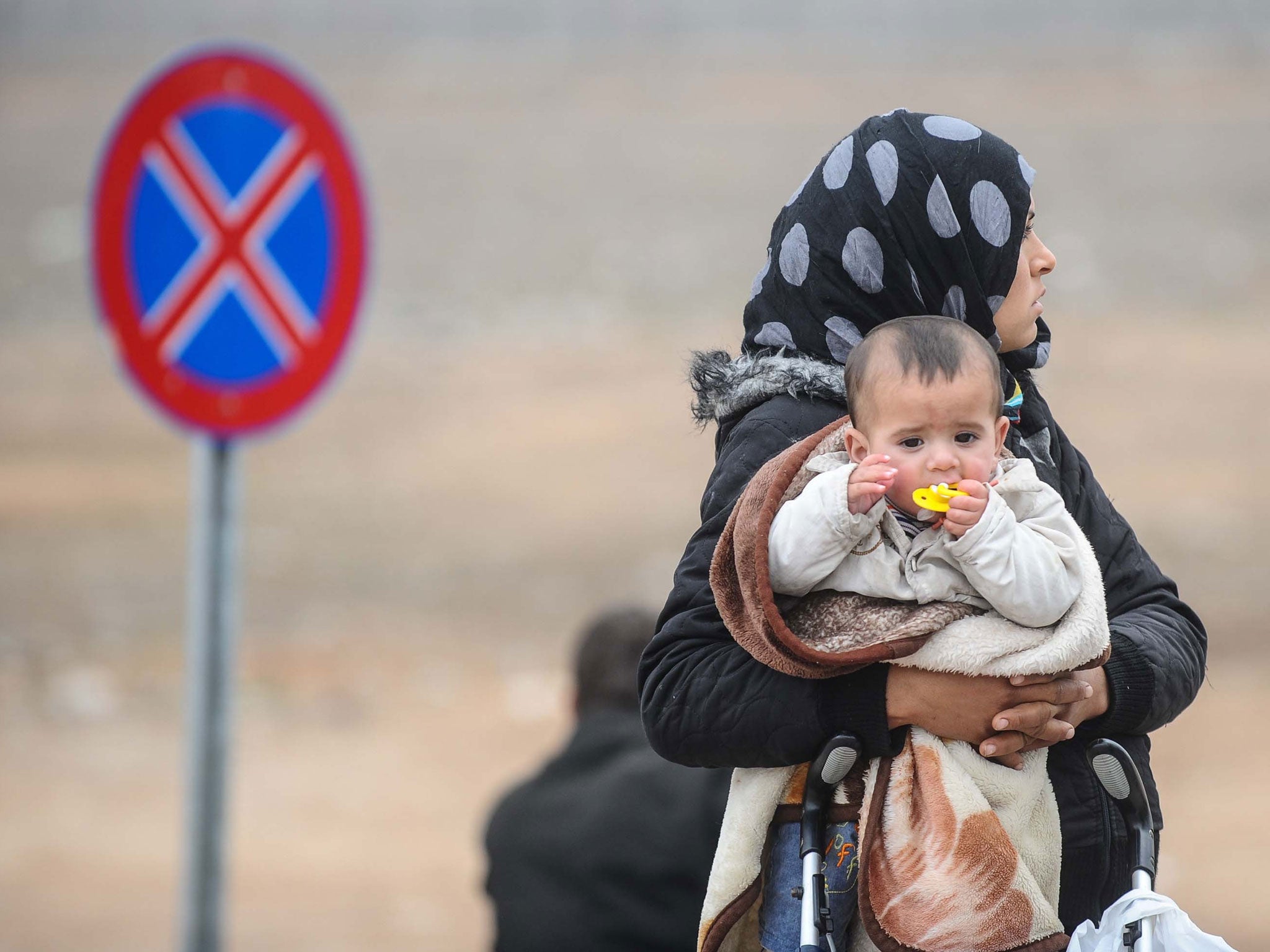 A Syrian woman with her baby at Syria's border with Turkey