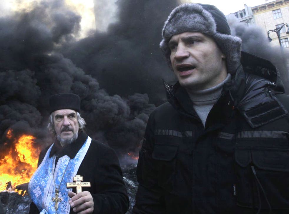 Opposition leader and former WBC heavyweight boxing champion Vitali Klitschko addresses protesters near the burning barricades between police and protesters in central Kiev