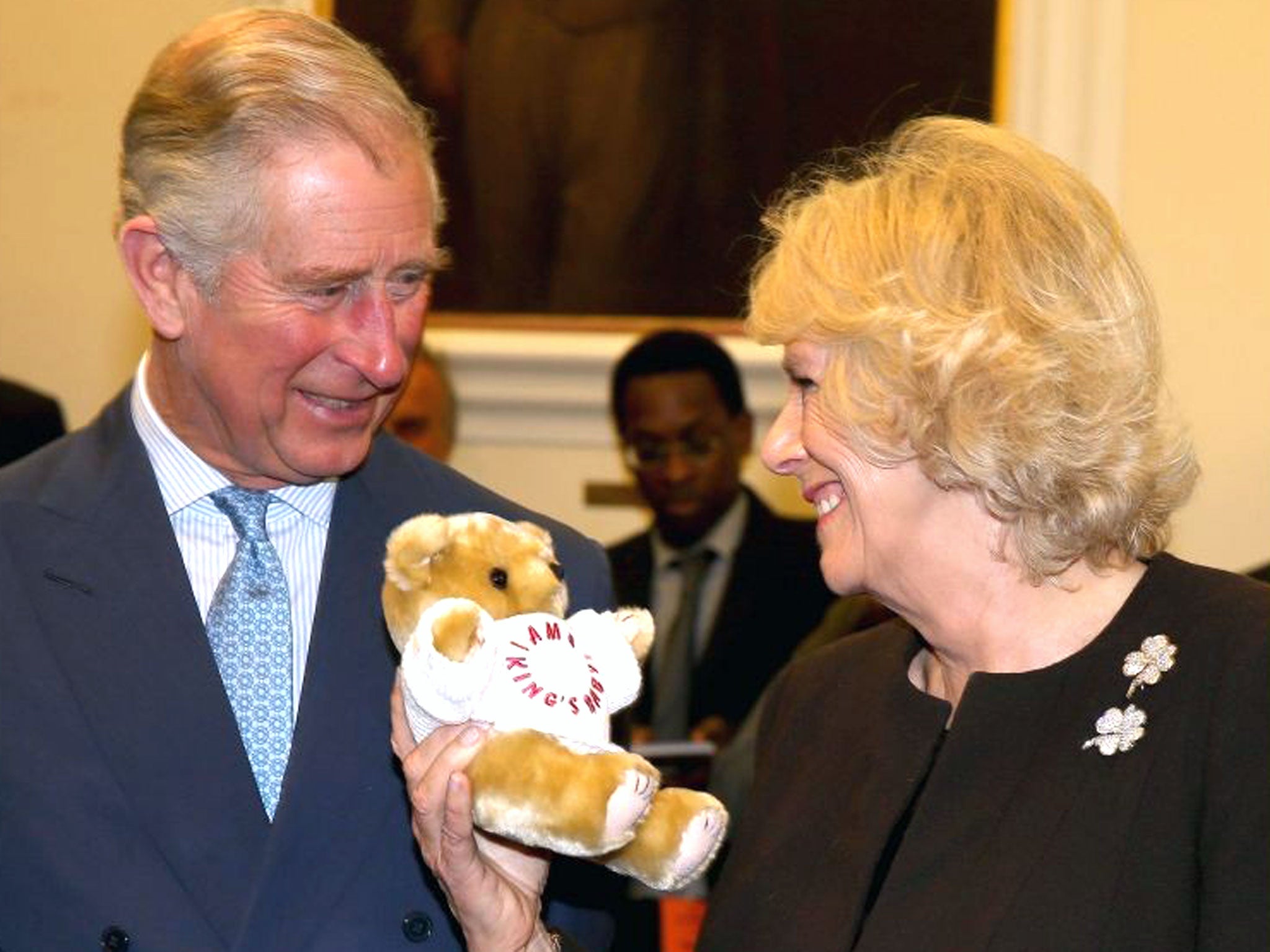 Camilla, Duchess of Cornwall holds an 'I'm a King's Baby' bear as Prince Charles, Prince of Wales looks on during an official visit to King's College Hospital in London