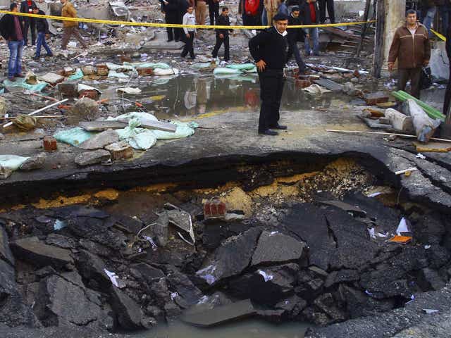 A police officer inspects a crater made after a bomb attack in front of Cairo Security Directorate building
