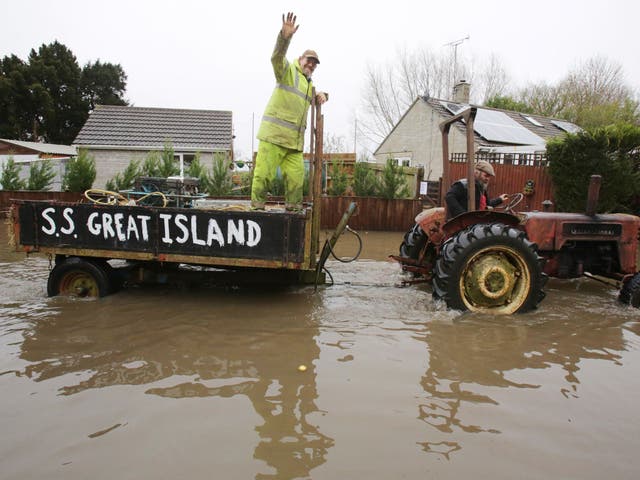 A vintage tractor drives through flooded Thorney 
