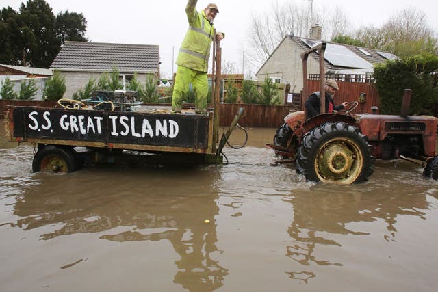 A vintage tractor drives through flooded Thorney 