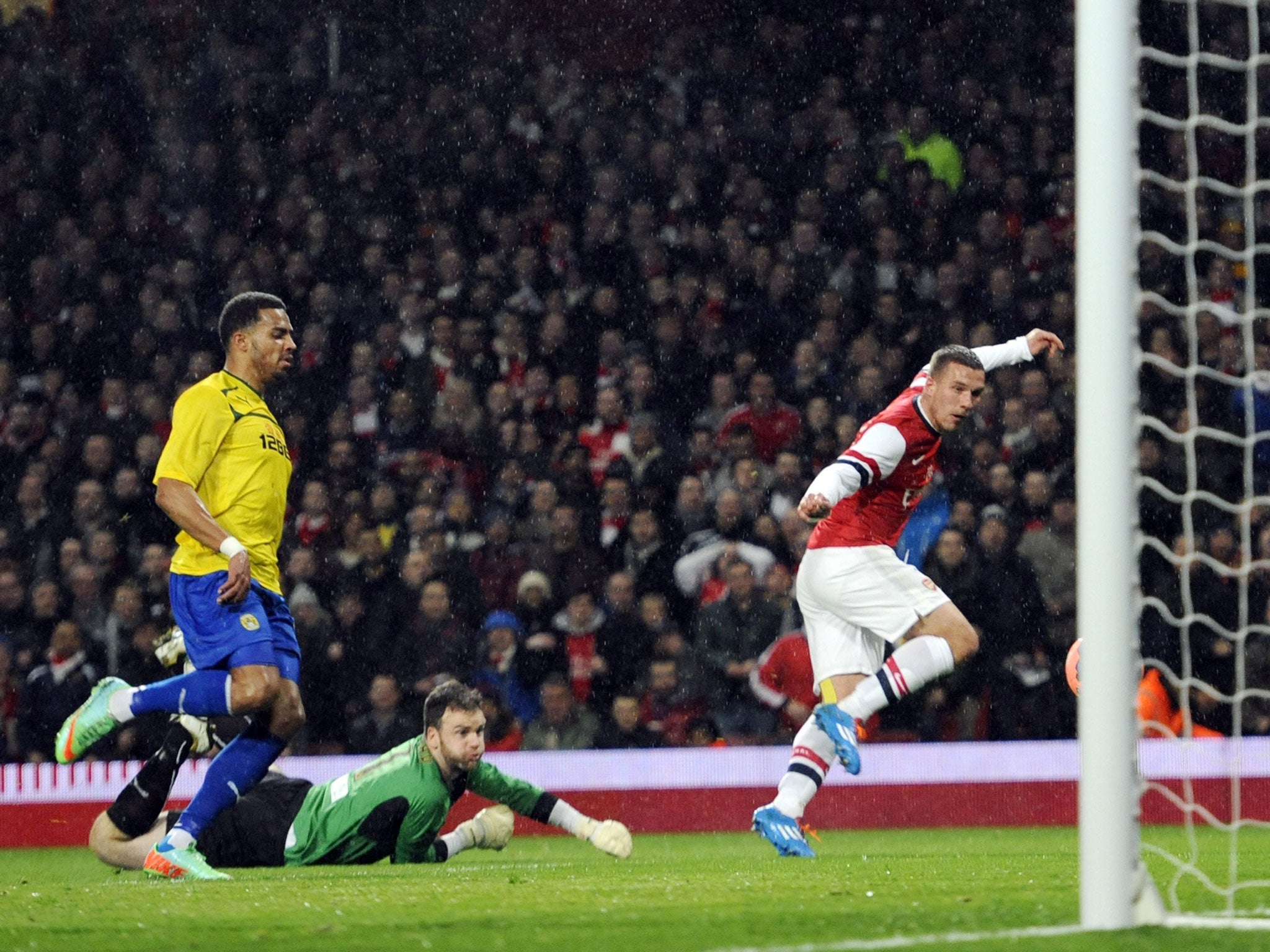 Lukas Podolski clips the ball just inside the post to score Arsenal's first goal