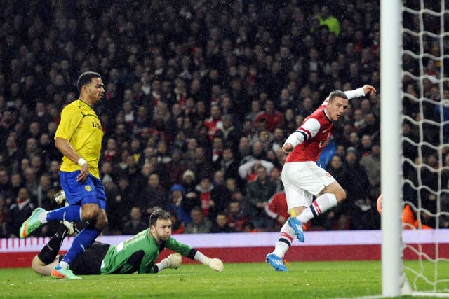Lukas Podolski clips the ball just inside the post to score Arsenal's first goal 