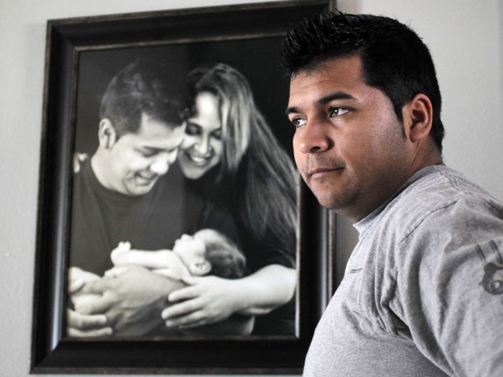 Erick Munoz stands with an undated copy of a photograph of himself, left, with wife Marlisa and their son Mateo