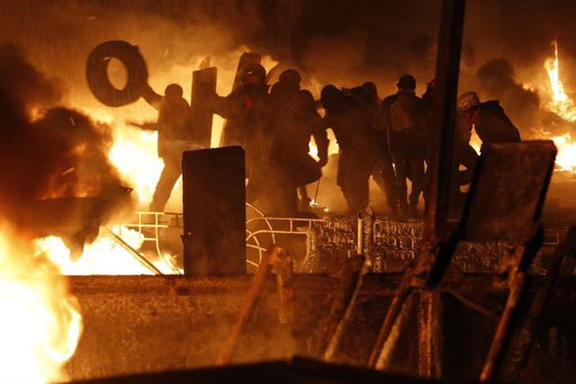 Anti-government protesters throw tyres at the site of clashes with riot police in Kiev 