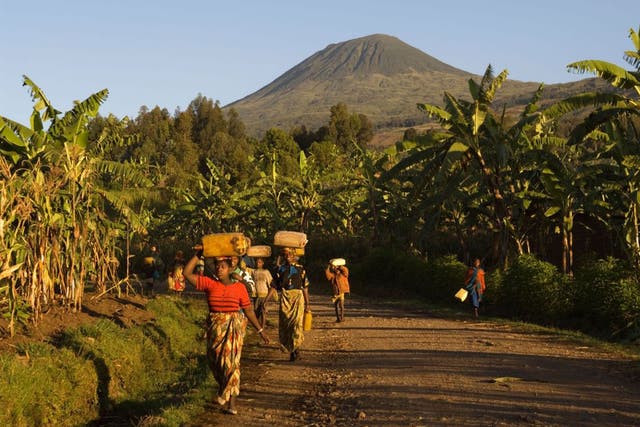 Women walk home with dormant volcano Muhabura in the background