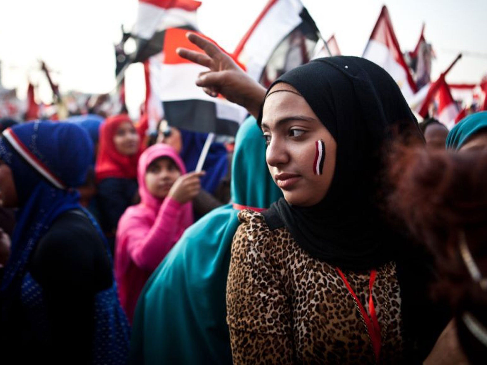 A girl looks on as around her thousands wave Egypt's national flag in Tahrir Square