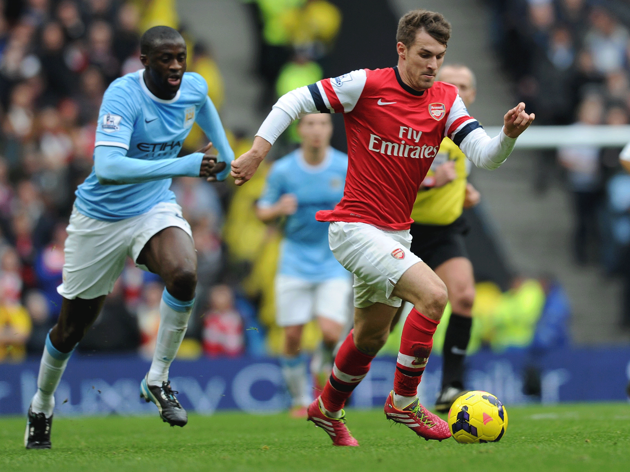 Aaron Ramsey runs past Manchester City midfielder Yaya Toure