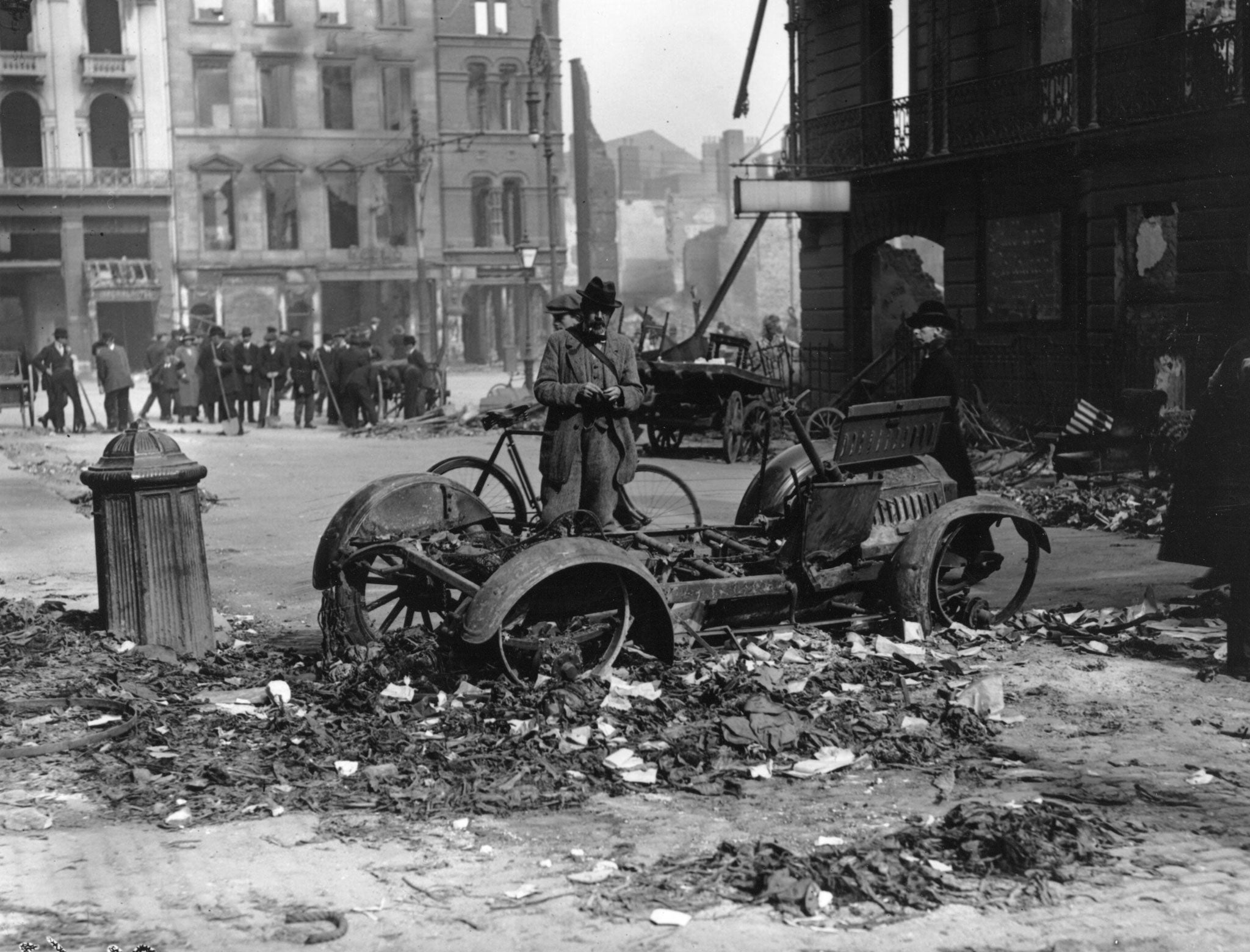 The aftermath of the Easter uprising with the ruins of a car in the foreground which has been used as a barricade