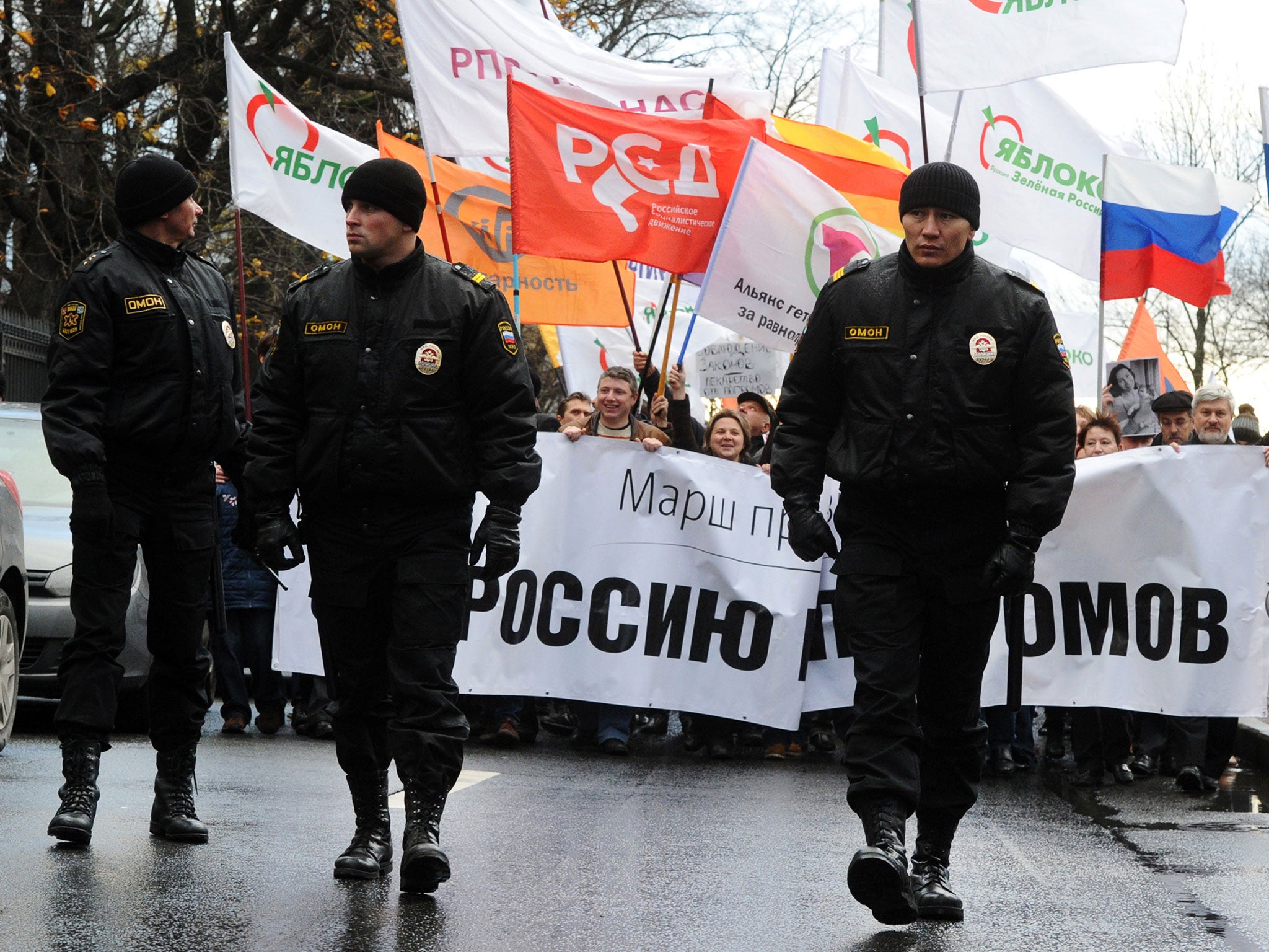 Russian riot police officers walk in front of protesters during the 'March against Hatred' in St. Petersburg in November 2013 (AFP/Getty)