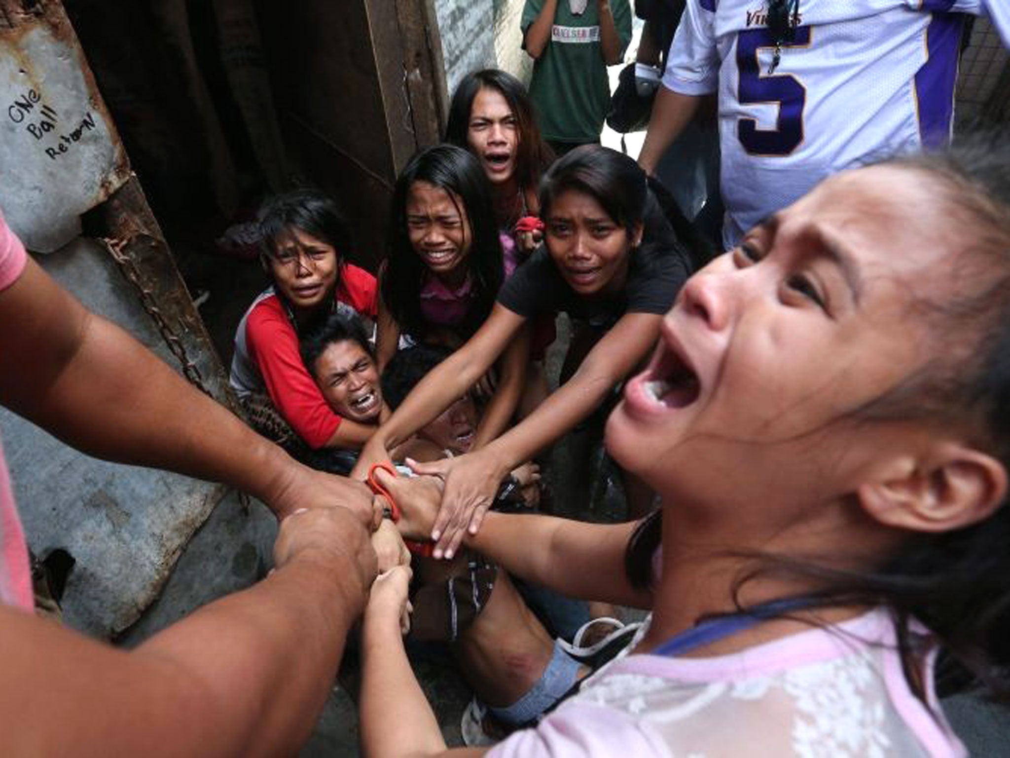 Filipino resident Brix Mercado (C) is being shielded by his family to prevent the local police from arresting him during a demolition of shanties at Sitio San Roque in Quezon City
