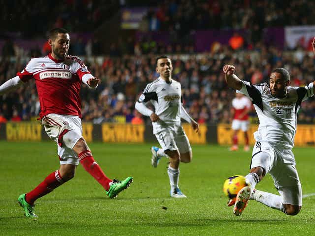 Clint Dempsey (L) of Fulham shoots as Ashley Williams (R) of Swansea City attempts to block 