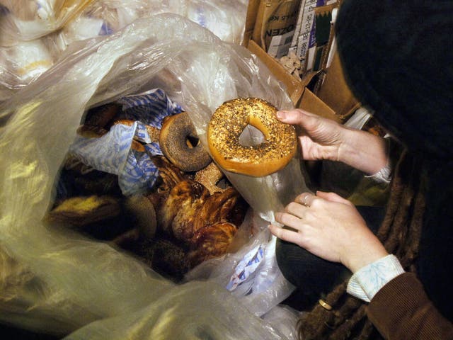 A freegan woman holds a bagel she found in a garbage bag outside a shop in New York, a practice allegedly used by the three men charged with vagrancy.  