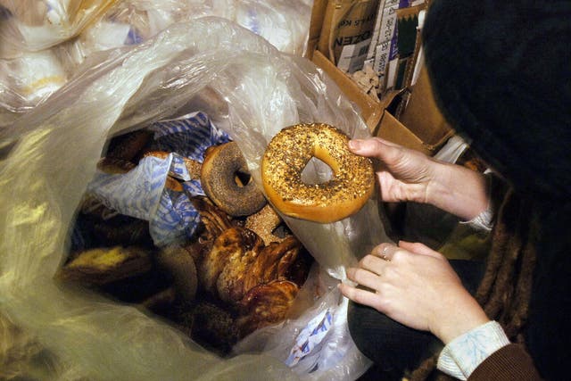 A freegan woman holds a bagel she found in a garbage bag outside a shop in New York, a practice allegedly used by the three men charged with vagrancy.  