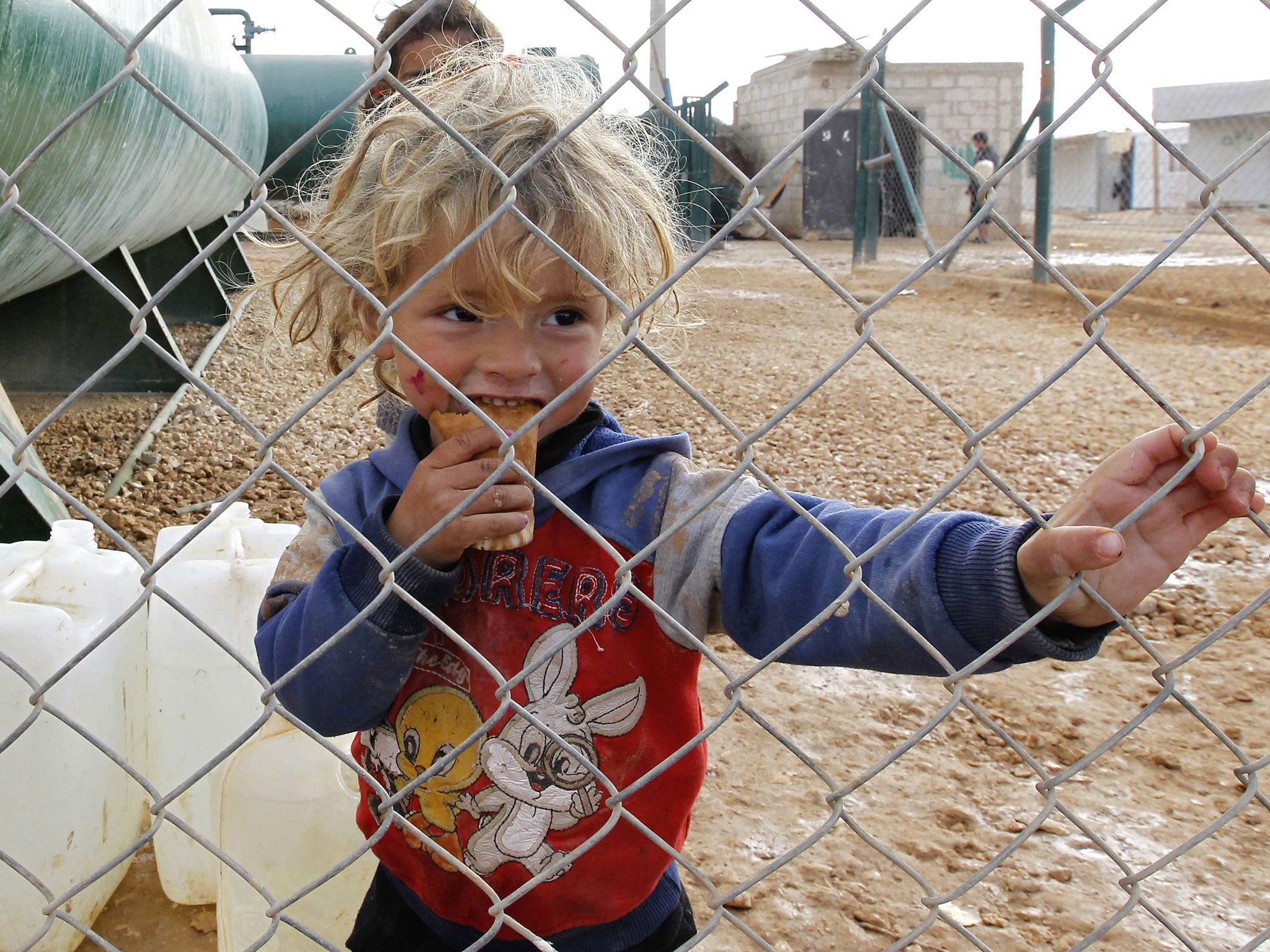 A young Syrian refugee stands near jerry cans used to collect water at Al-Zaatri refugee camp in the Jordanian city of Mafraq, near the border with Syria. The United Nations hopes that political talks between the warring sides in Syria will clinch local ceasefires to allow vital food and medicines to reach millions of civilians