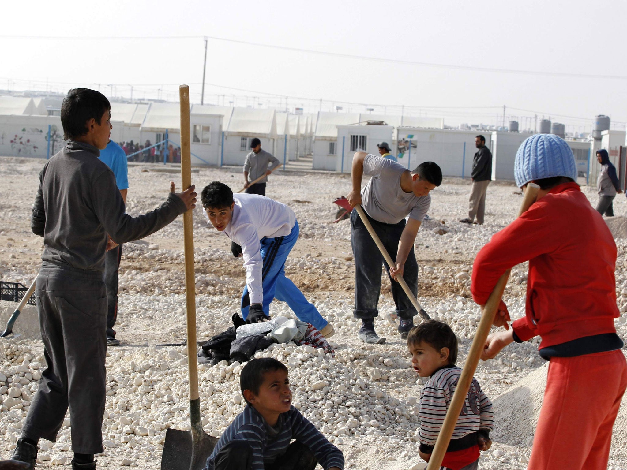Syrian refugees transport small stones for their tents at Al Zaatari refugee camp in the Jordanian city of Mafraq, near the border with Syria