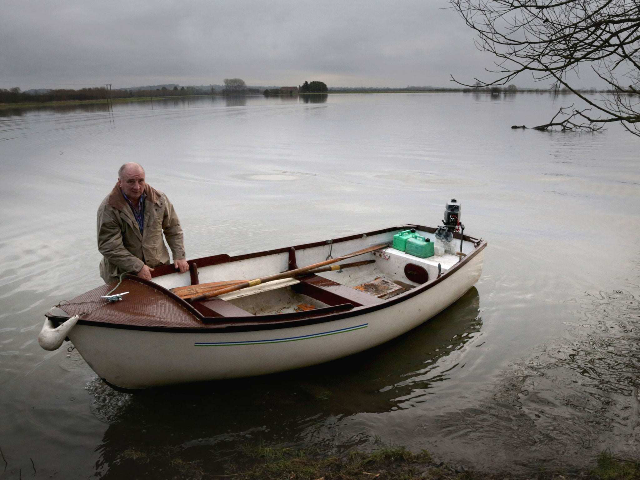 Farmer Roger Forgan uses a boat to cross farm land in front of his flooded farm which has been cut off by flood waters at Muchelney near Langport in Somerset