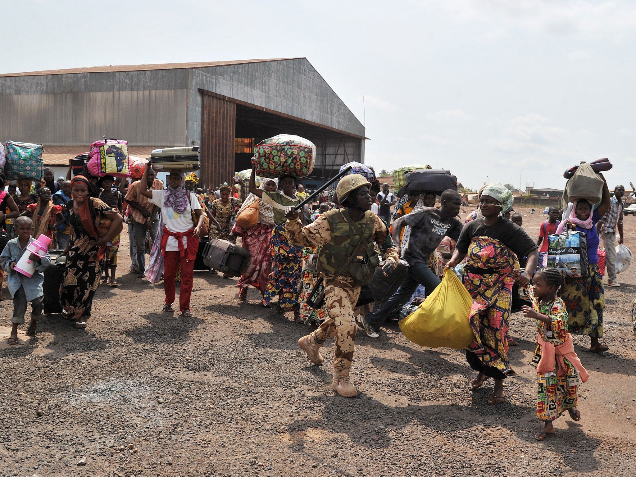 A Chadian MISCA peacekeeper (C) runs to control the crowds as Chadian nationals and other foreign civilians, mostly Muslims, rush to board a plane bound for N'Djamena in order to flee Bangui to avoid being targeted by Anti-Balaka Christian militants