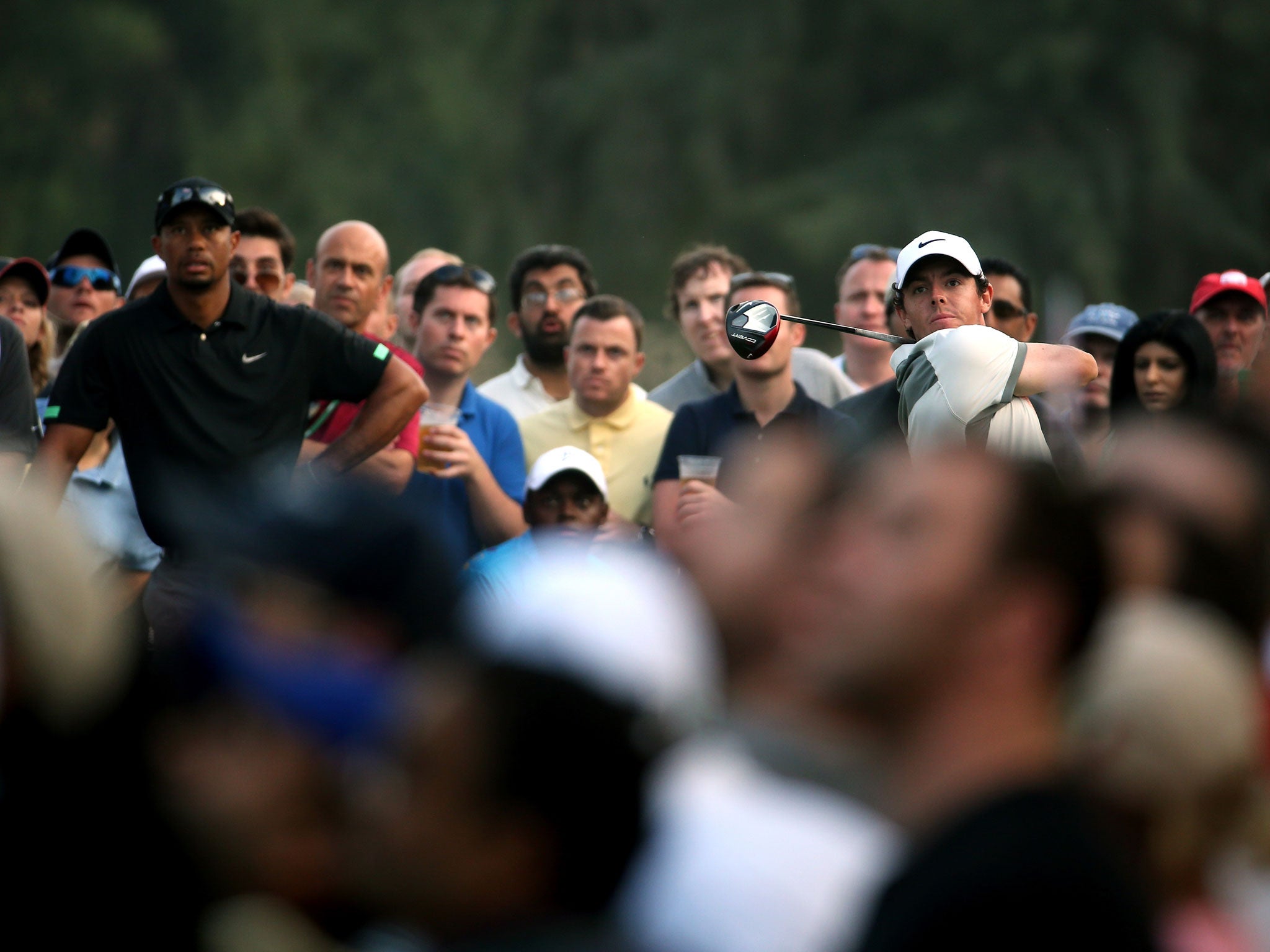 Rory McIlroy of Northern Ireland tees off on the 18th hole during the second round of the 2014 Omega Dubai Desert Classic watched by Tiger Woods (Getty Images)