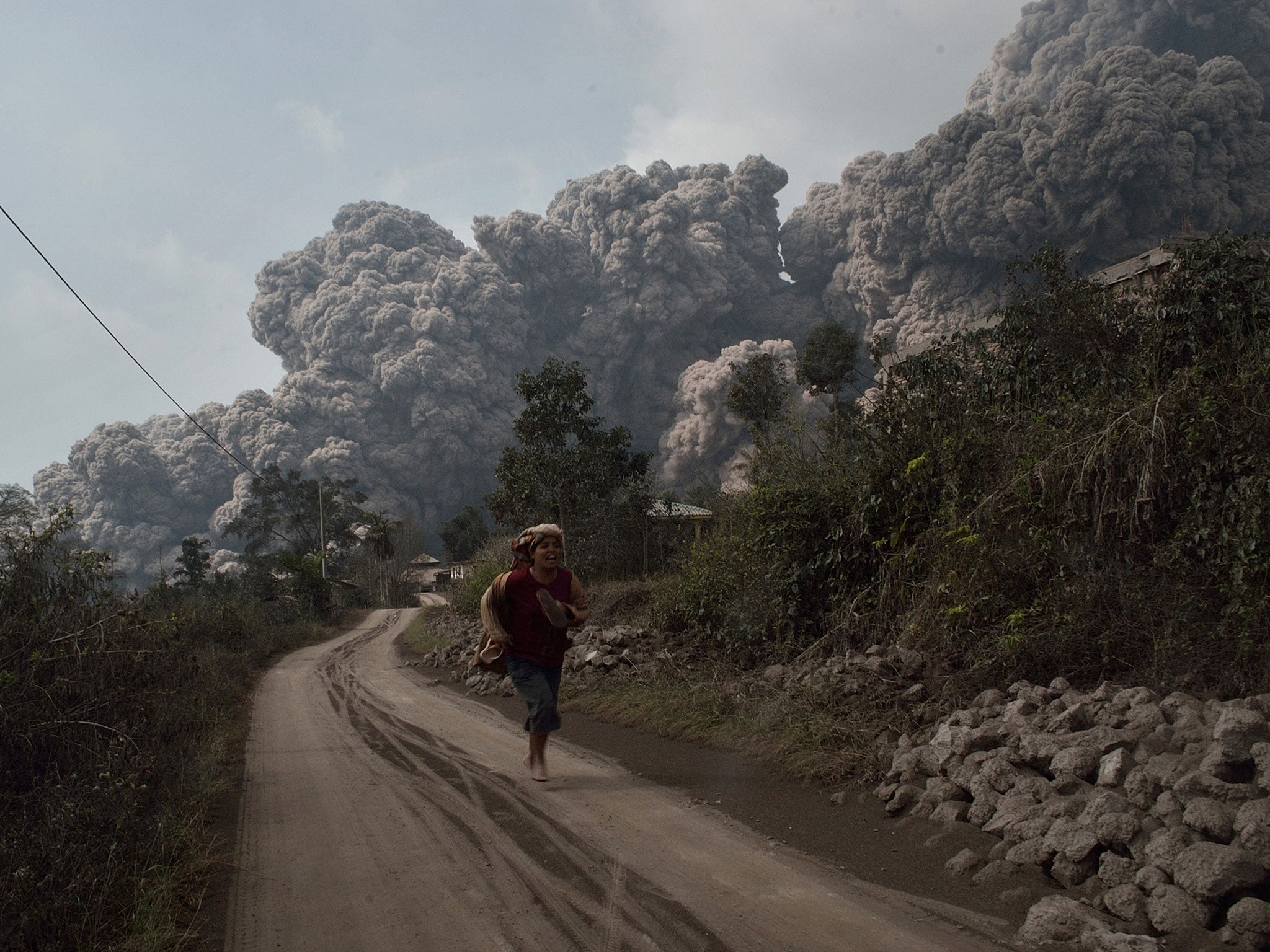 A resident runs away to escape from hot volcanic ash clouds engulfing villages in Karo district during the eruption in Sumatra.