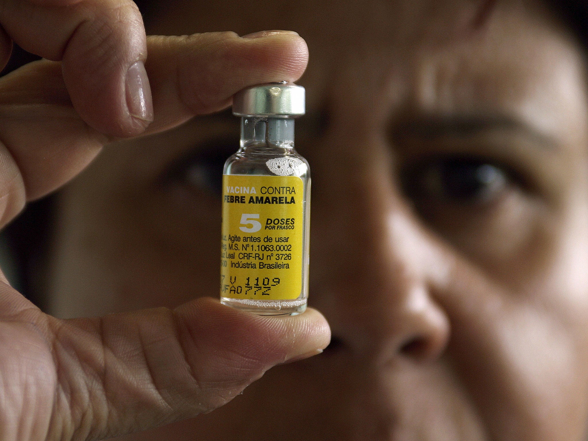 A nurse holds up a vaccine of yellow fever, which is currently in short supply around the world