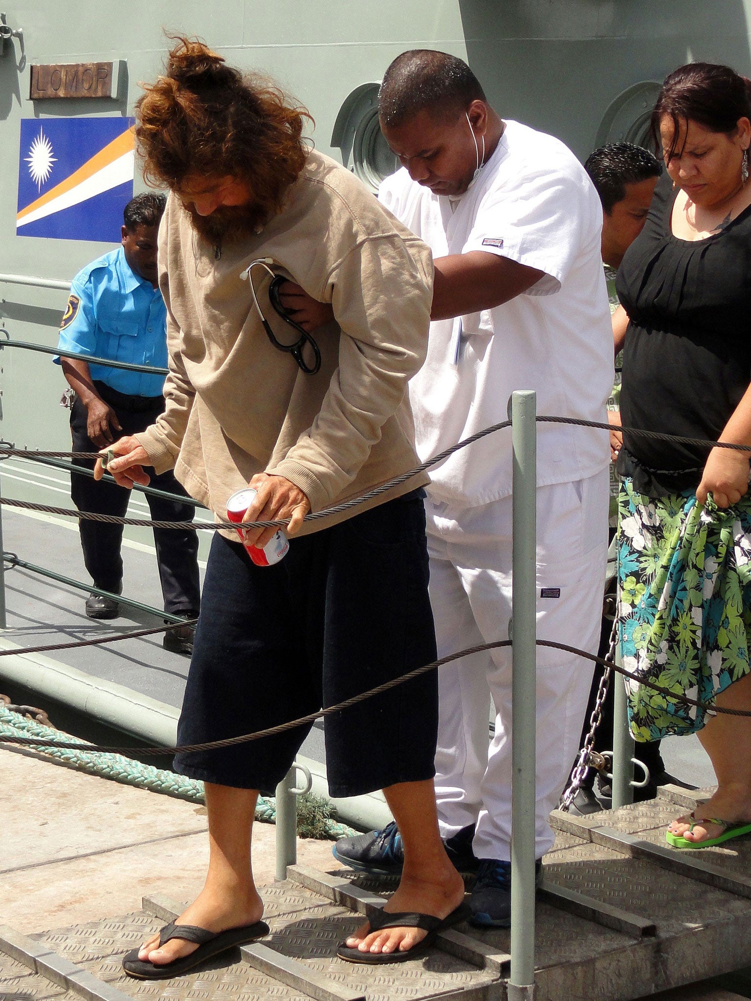 A Mexican castaway steps off a sea patrol vessel in Majuro with the help of a nurse after a 22-hour boat ride from isolated Ebon Atoll on February 3, 2014