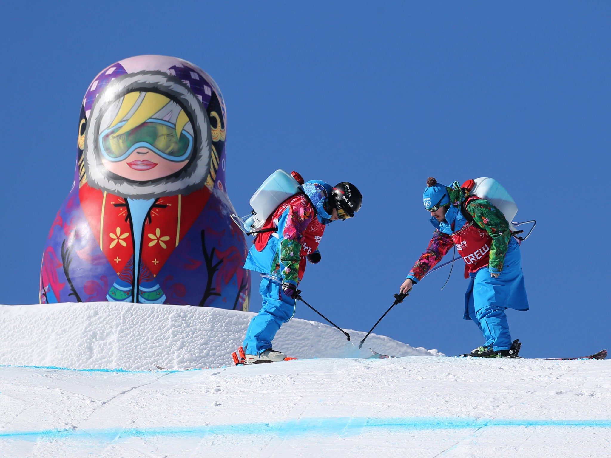 Workers spray paint on the slopestyle course at the Rosa Khutor Extreme Park