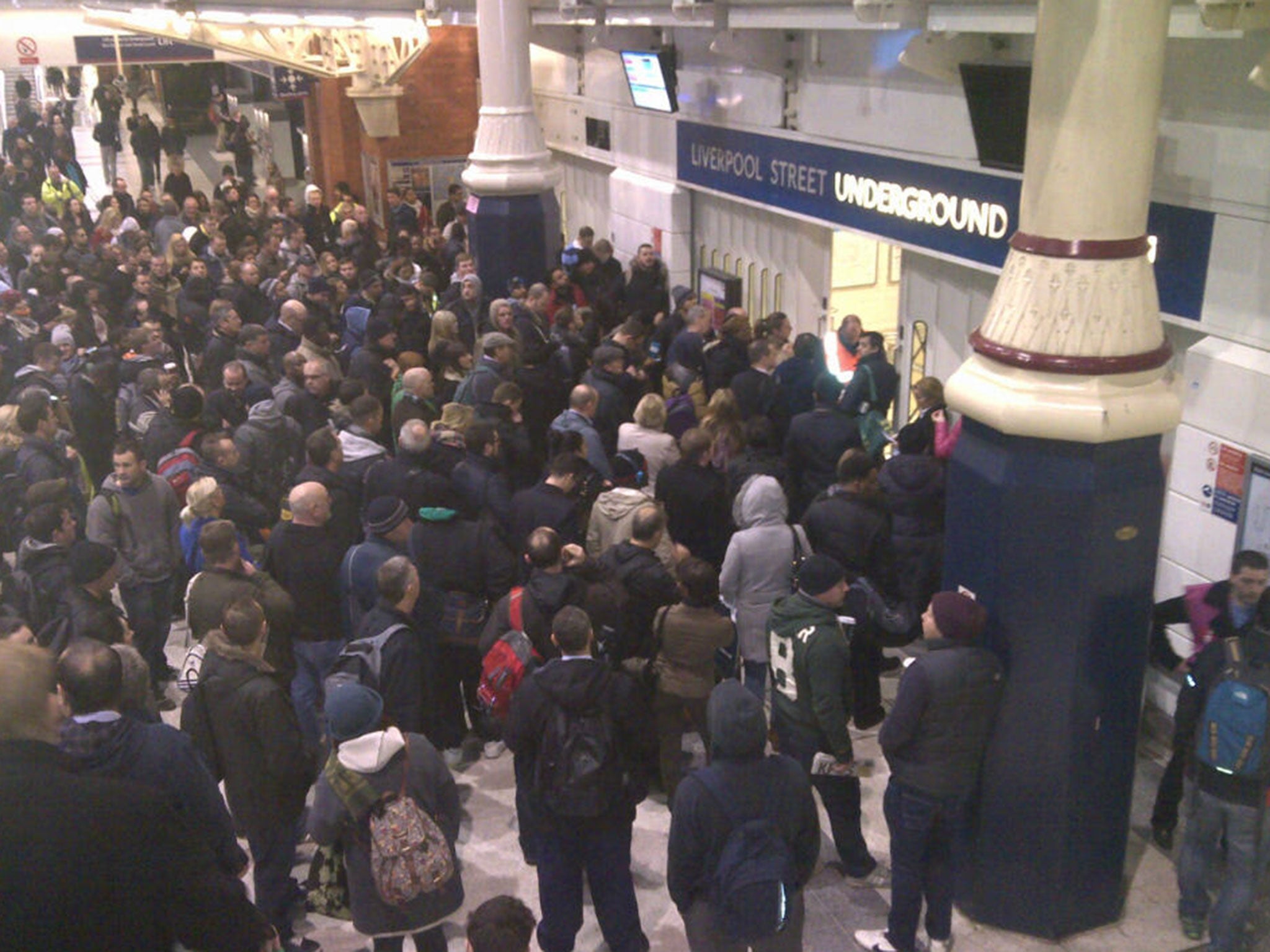 Commuters wait for gates to open to the District Line at Liverpool Street station at 7am this morning