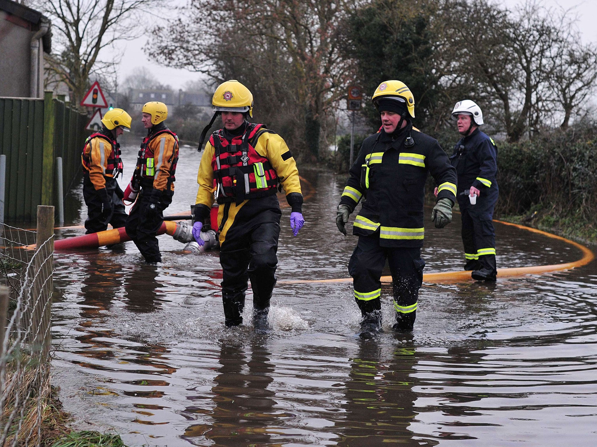 Firemen attempt to pump water off a flooded road near Long Load in Somerset, south west England on January 30, 2014