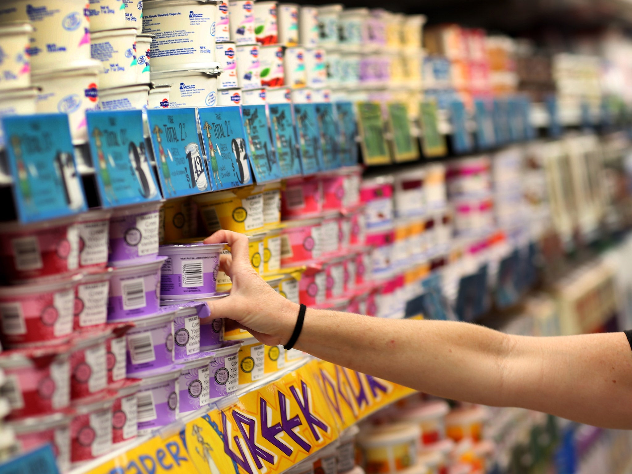 A supermarket customer grabs a pot of yoghurt from the shelf