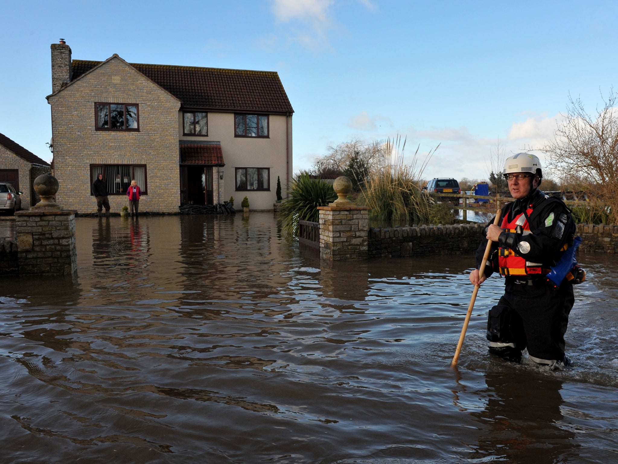 An emergency worker walks down the road outside a property in Moorland, Somerset, after residents were advised to evacuate after flood defences were breached overnight