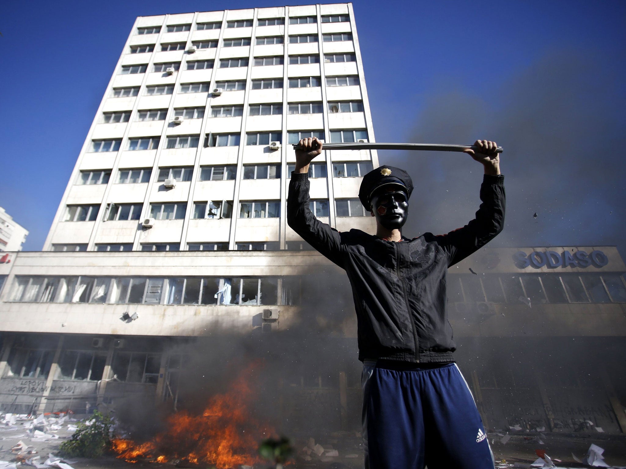 A protester stands near a fire set in front of a government building in Tuzla