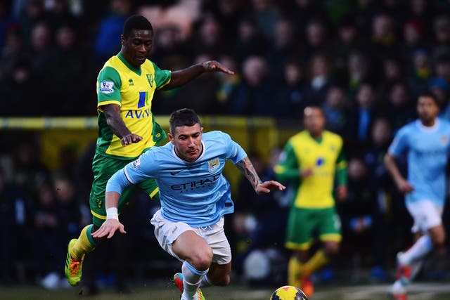 Manchester City defender Aleksandar Kolarov falls to the under pressure from Norwich midfielder Alexander Tettey 