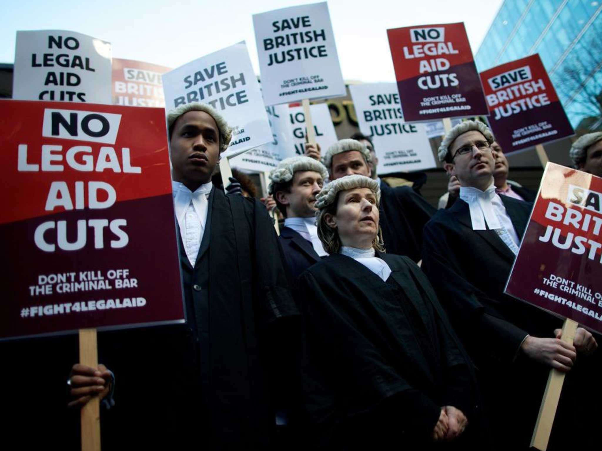 Legal professionals hold placards during a protest against cuts to the legal aid budget