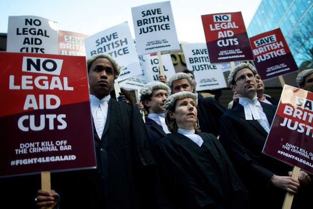 Legal professionals hold placards during a protest against cuts to the legal aid budget