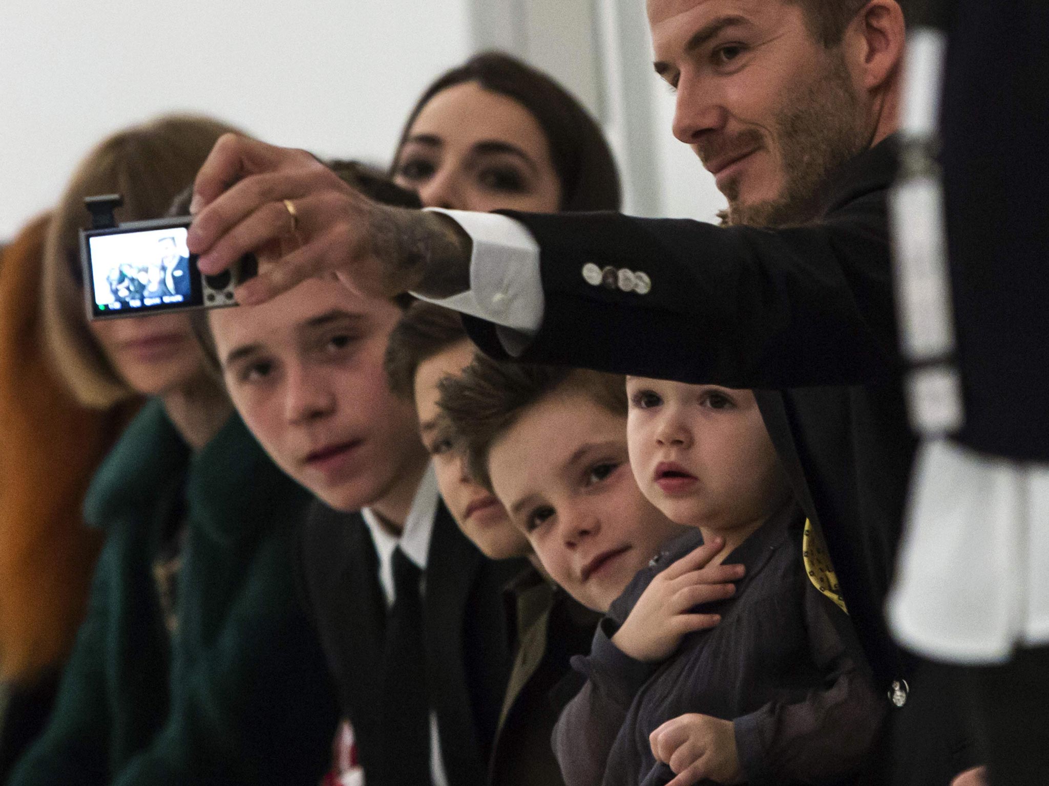 David Beckham photographs his children on the front row