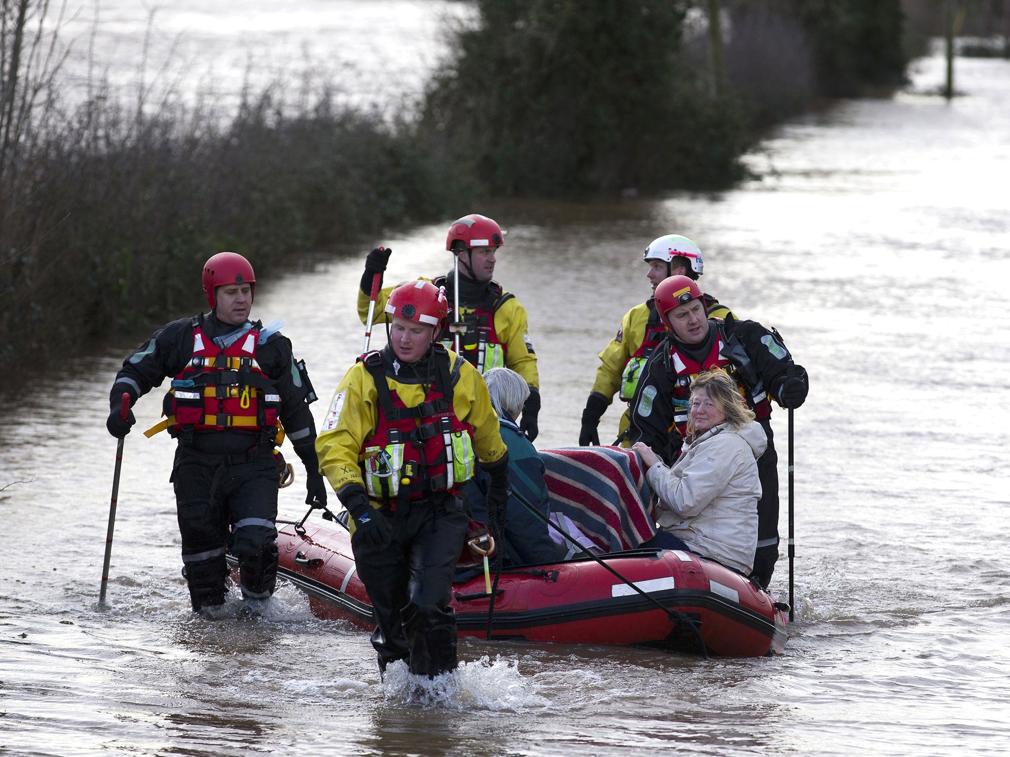 Devon and Somerset Fire and rescue service evacuate two women and two cats in baskets through flood waters in Burrowbridge