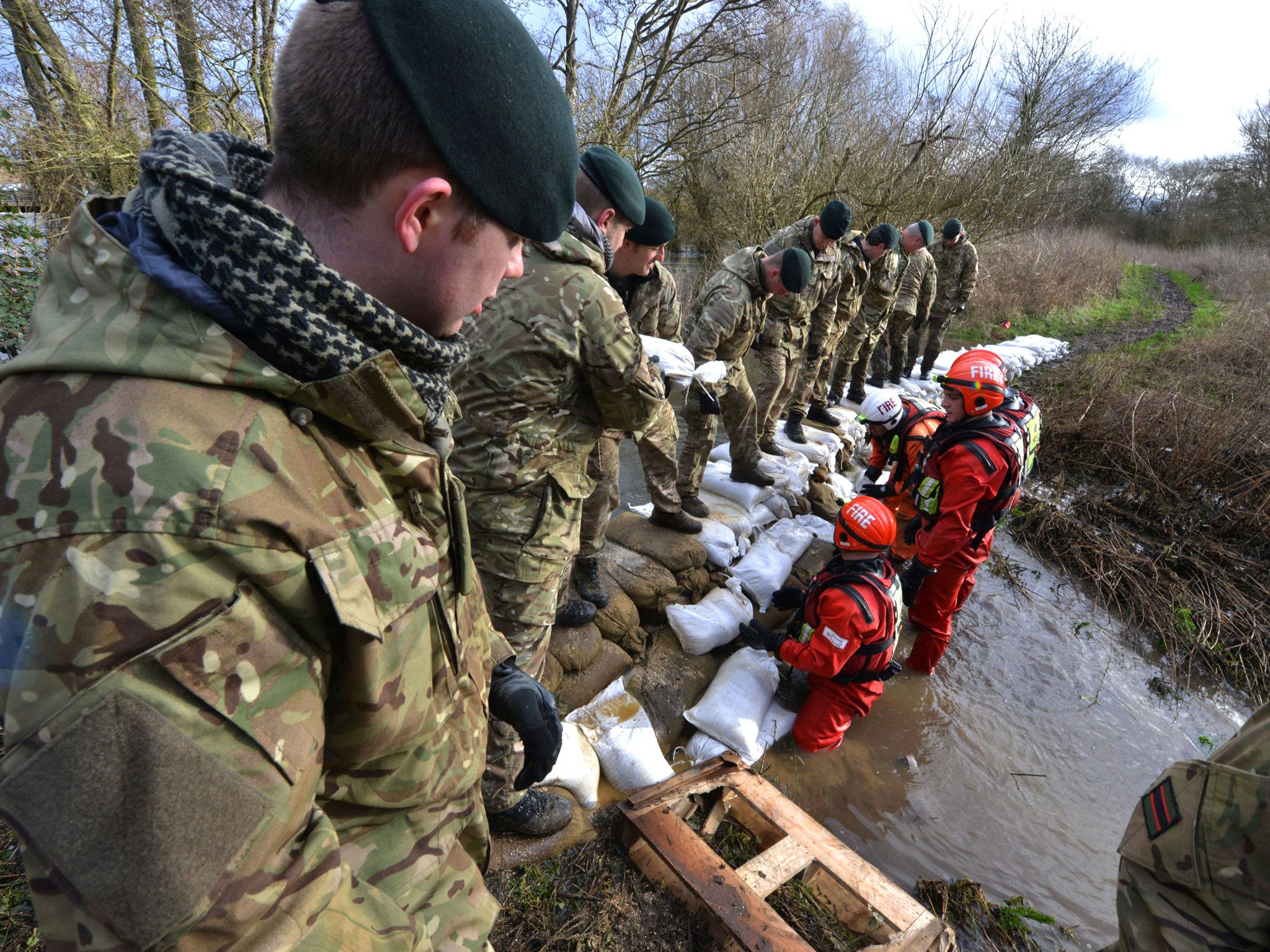 Reserve soldiers of 7 Battalion The Rifles, deployed alongside members of Berkshire Fire and Rescue Service, working hard to dam a breach in the Kennet Canal that threatened an electrical sub-station near Burghfield, south of Reading, as the military were