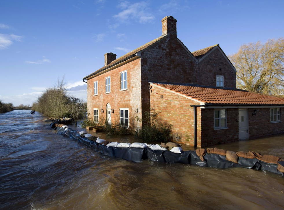 Flood waters engulf a house with a wall of sandbags around it in Burrowbridge
