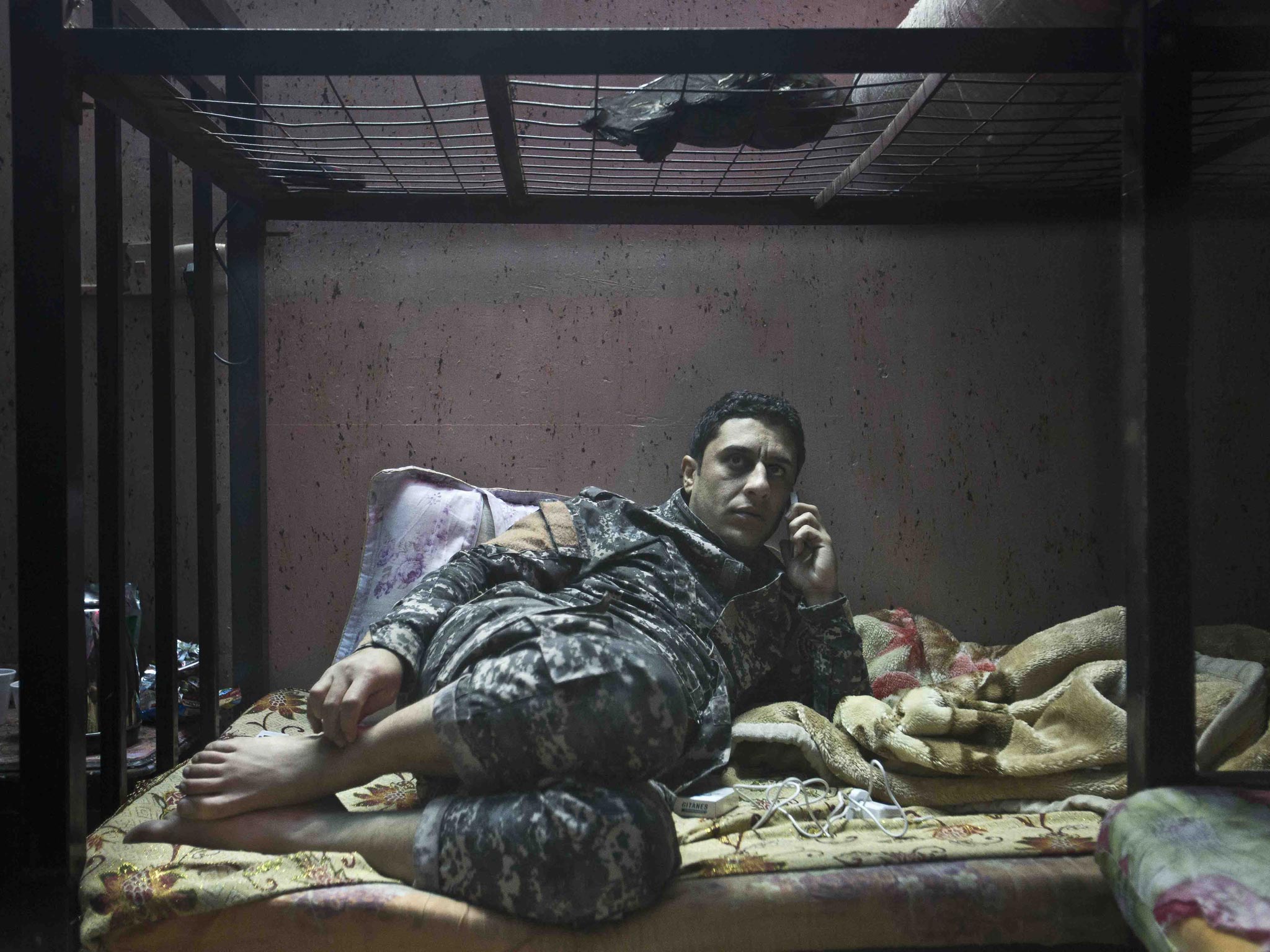 No rest for those who hunt the wicked: Ali, a member of The Hawks, sits on his bunk bed while on stand-by at the team’s barracks in Baghdad