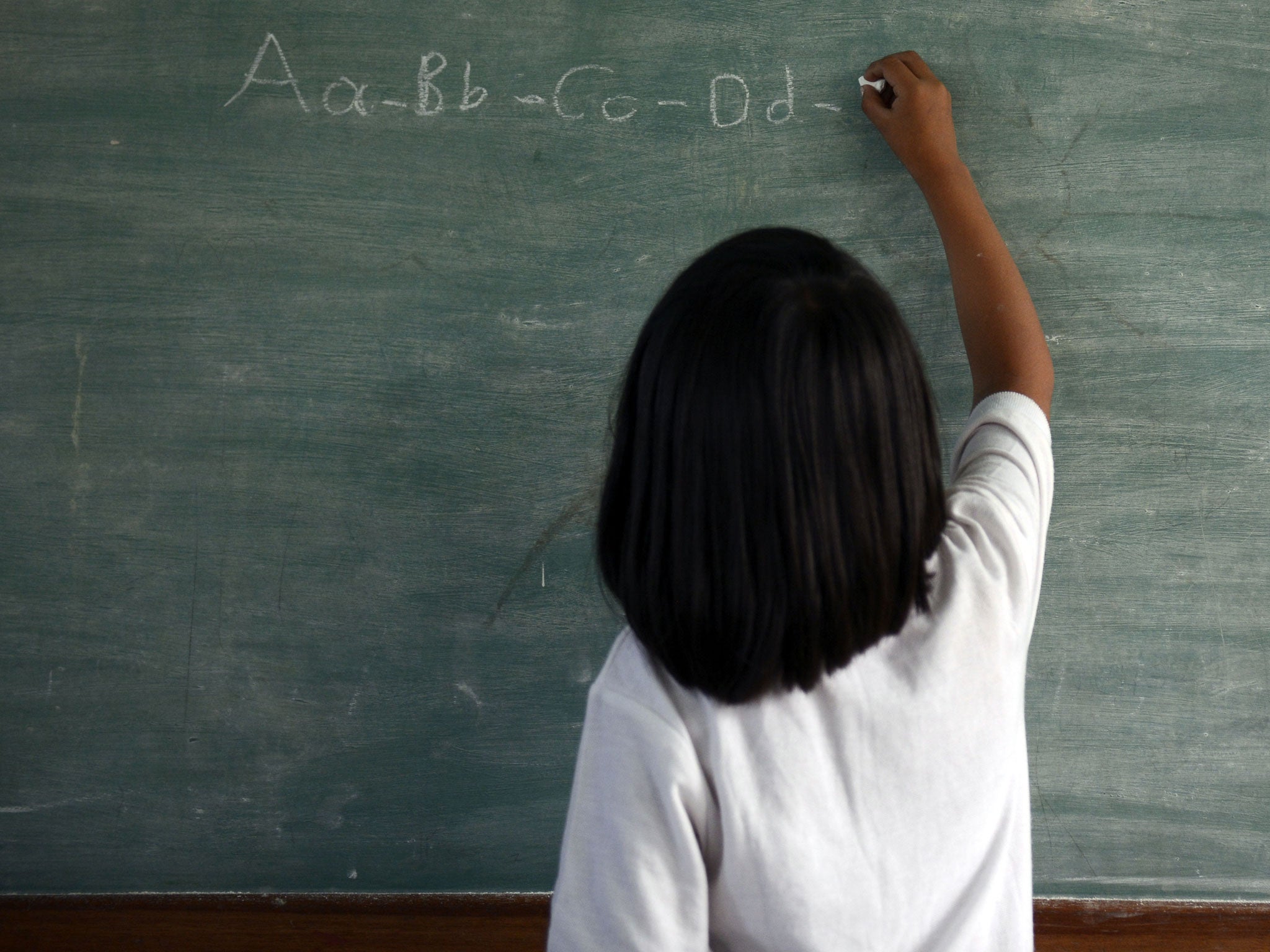 A child writes on a chalkboard. Research by the Ambitious about Autism charity has shown that children with the condition are often informally excluded from school activities.