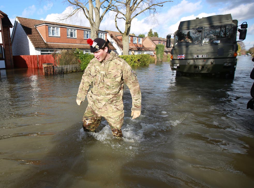 A member of the 1st Battalion of the Royal Regiment of Fusiliers leads his vehicle through flood water in Wraysbury